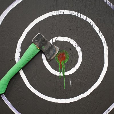 Axe with green handle embedded in bullseye on black target.