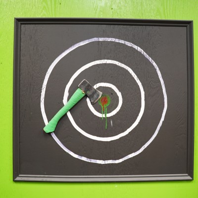 Axe embedded in a target on a bright green background.