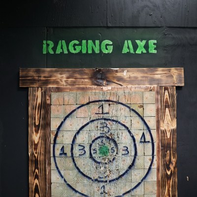 Axe throwing target with numbered circles under 'Raging Axe' sign.