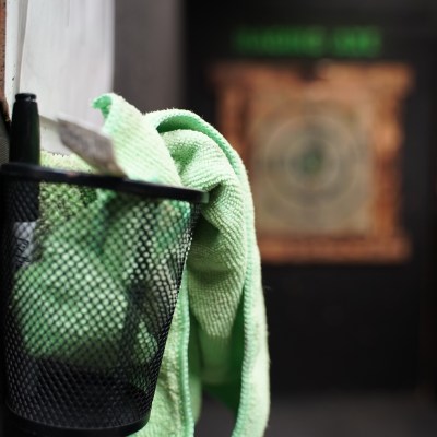 Pen and cloth in a mesh holder with blurred dartboard in the background.