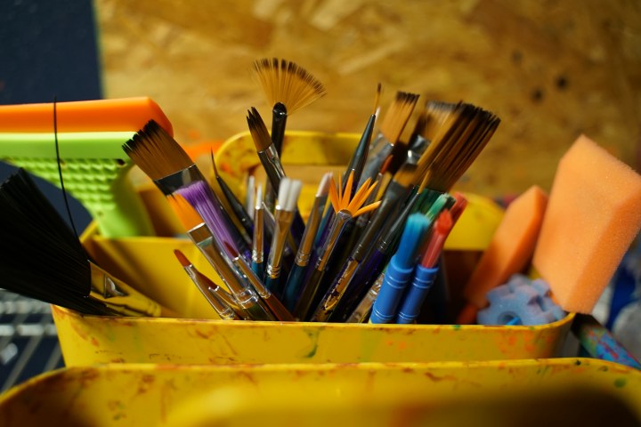 Assorted paintbrushes and sponges in a colorful holder.