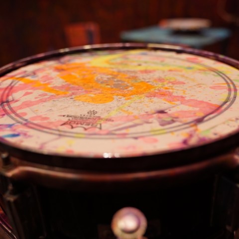 Close-up of a drum with a colorful, paint-splattered surface.