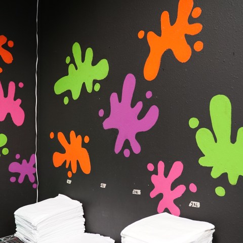 Colorful paint splatters on a black wall above folded white towels.