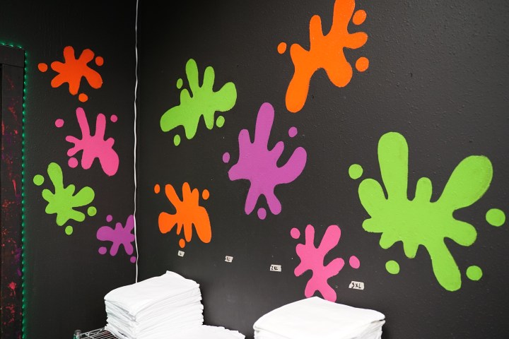 Colorful paint splatters on a black wall above folded white towels.