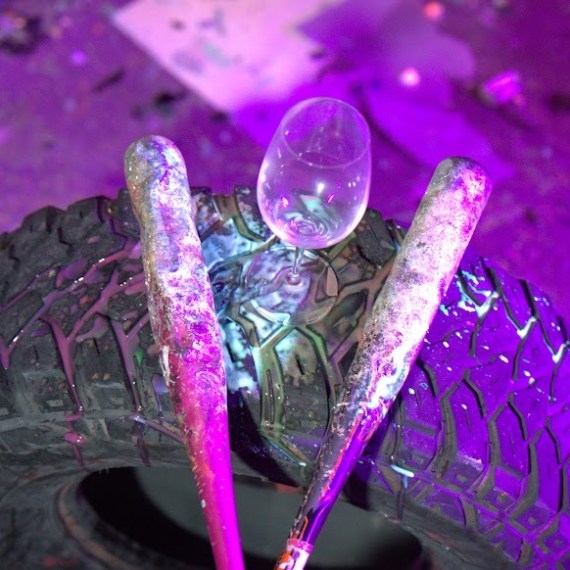 Tire with two paint-splattered bats and an upside-down wine glass, under purple lighting.
